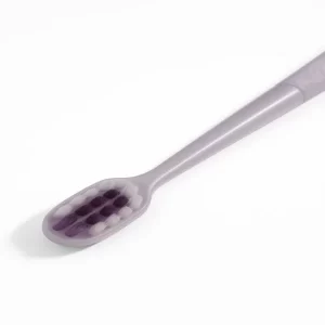 A front view of the Ultra Soft Nano Toothbrush standing next to its open plastic hygienic travel case.