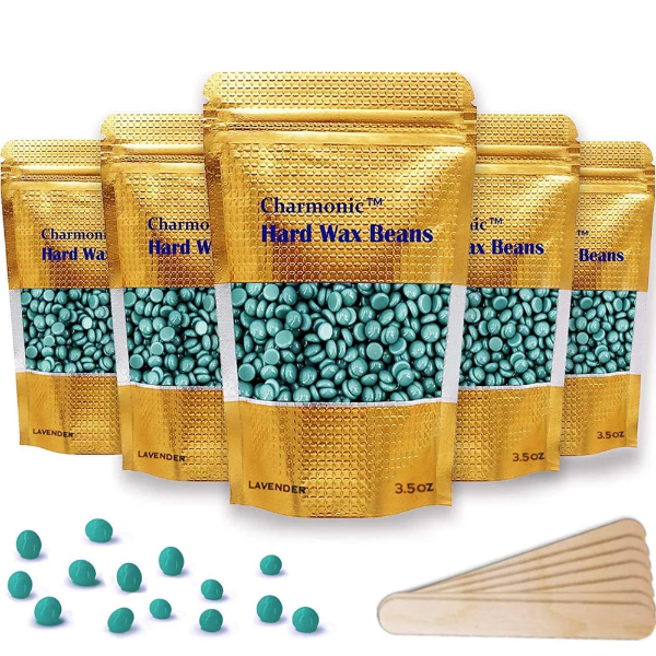 A bag of Charmonic chamomile hair removal wax beans surrounded by scattered yellow wax beads on a vanity