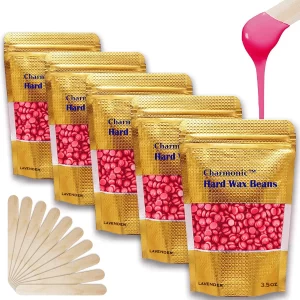 A bag of Charmonic rose body wax beans surrounded by scattered pink wax beads on a vanity
