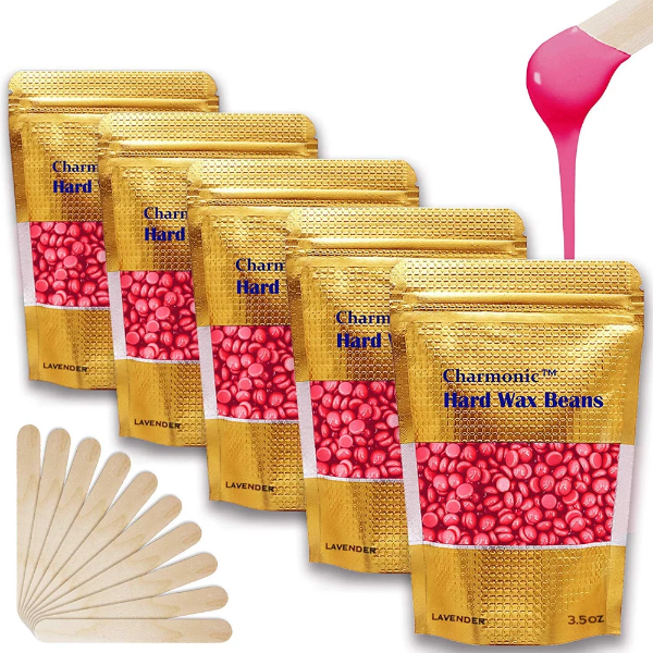 A bag of Charmonic rose body wax beans surrounded by scattered pink wax beads on a vanity
