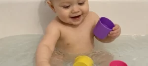 Baby playing with floating bath cups in a bathtub