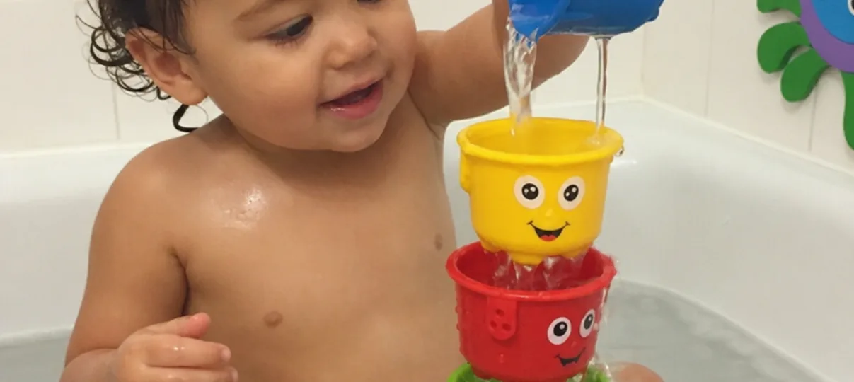 Toddler Pouring Water Through Bath Toy Cups Toddler pouring water through colorful bath toy cups